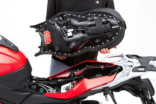 a person holding Canyon Dual Sport seat showing the back side heater wiring, MPN printed and mounting brackets pre-installed