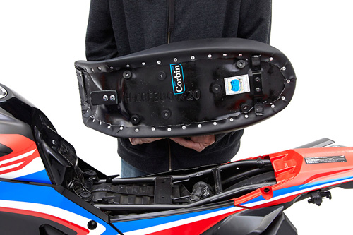 a person holding Dual Sport seat showing the back side, MPN printed and mounting brackets pre-installed