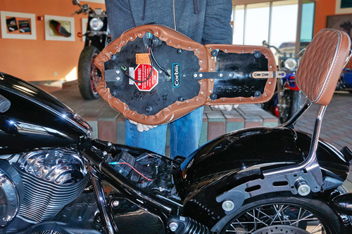 a person holding Front & Rear seat showing the back side heater wiring, MPN printed and mounting brackets pre-installed