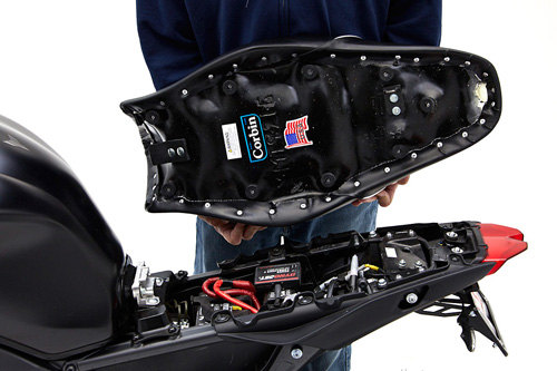 a person holding Gunfighter seat showing the back side, MPN printed and mounting brackets pre-installed