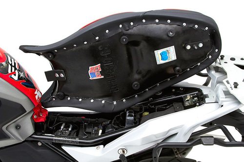 a person holding Canyon Dual Sport seat showing the back side, MPN printed and mounting brackets pre-installed