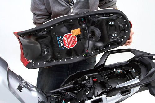 a person holding High Dual seat showing the back side heater wiring, MPN printed and mounting brackets pre-installed