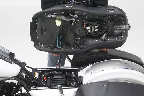 a person holding Dual Touring seat showing the back side heater wiring, MPN printed and mounting brackets pre-installed