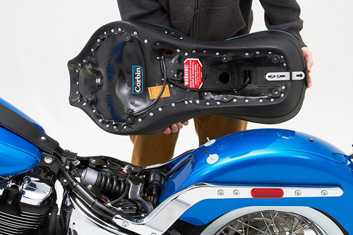 a person holding Dual Touring seat showing the back side heater wiring, MPN printed and mounting brackets pre-installed
