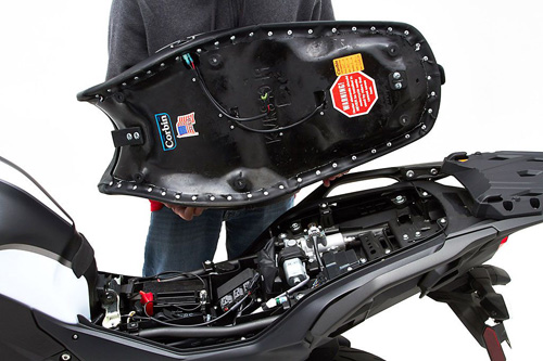 a person holding Canyon Dual Sport seat showing the back side heater wiring, MPN printed and mounting brackets pre-installed