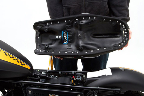 a person holding Gunfighter & Lady seat showing the back side heater wiring, MPN printed and mounting brackets pre-installed