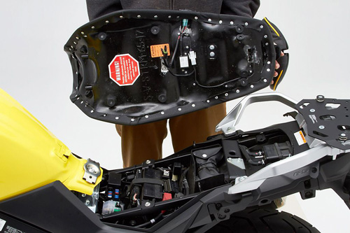 a person holding Canyon Dual Sport seat showing the back side heater wiring, MPN printed and mounting brackets pre-installed