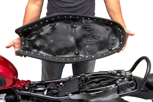 a person holding Classic Gunfighter seat showing the back side, MPN printed and mounting brackets pre-installed