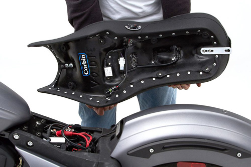 a person holding Dual Touring seat showing the back side heater wiring, MPN printed and mounting brackets pre-installed