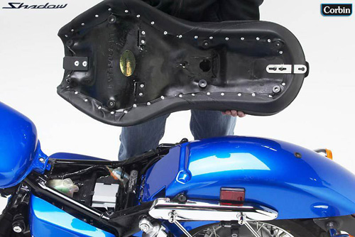 a person holding Dual Tour seat showing the back side, MPN printed and mounting brackets pre-installed