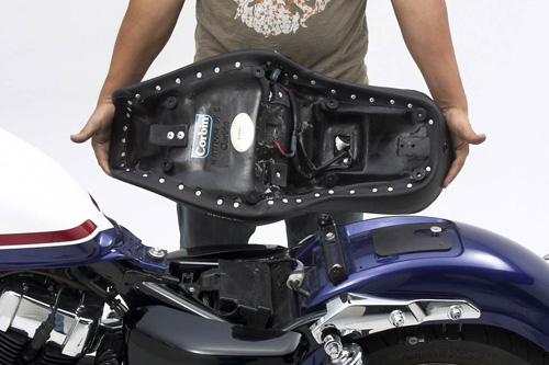 a person holding Dual Tour seat showing the back side heater wiring, MPN printed and mounting brackets pre-installed