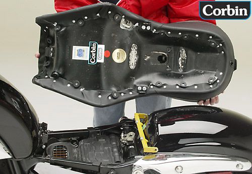 a person holding Dual Tour seat showing the back side mounting brackets pre-installed and airbox is also shown