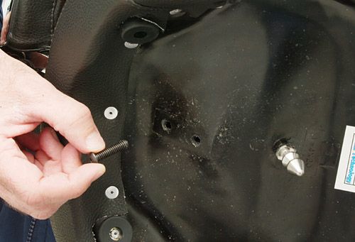 a person is inserting a bolt into either of the two openings in the Corbin basepan to adjust the position of the Corbin backrest