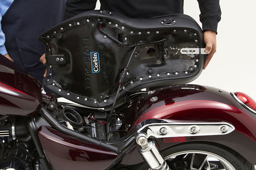 a person holding Dual Touring seat showing the back side heater wiring, MPN printed and mounting brackets pre-installed