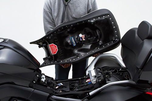a person holding Dual Touring seat showing the back side heater wiring, MPN printed and mounting brackets pre-installed