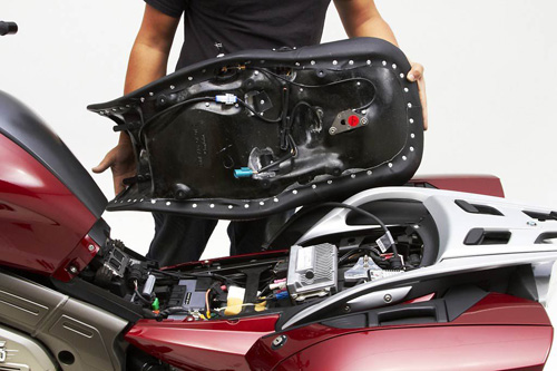 a person holding Dual Tour seat showing the back side heater wiring, new keylock system, MPN printed and mounting brackets pre-installed