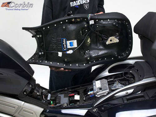 a person holding Dual Tour seat showing the back side heater wiring, new keylock system, MPN printed and mounting brackets pre-installed