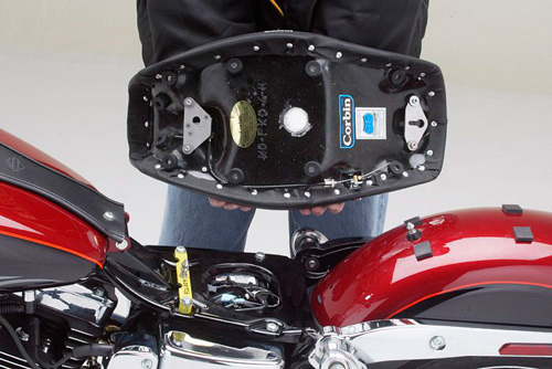 a person holding Hollywood Solo seat showing the rear side, MPN printed, stainless steel catch pin into the fender location shown, keyhole bracket at the bottom of the seat will integrate with this pin