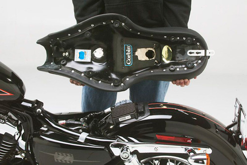 a person holding Gunfighter & Lady seat showing the rear side new key-lock system, MPN printed and mounting brackets pre-installed