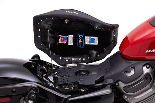 a person holding Hollywood Solo seat showing the rear side, Corbin sticker America Flag and mounting brackets(Hinge system) pre-installed