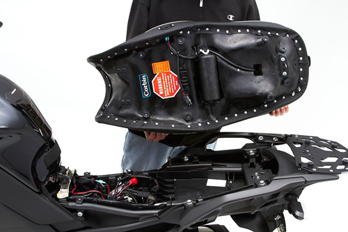 a person holding Canyon Dual Sport seat showing the heater wiring, MPN printed and mounting brackets pre-installed