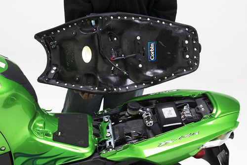 a person holding Canyon Dual Sport seat showing the heater wiring, MPN printed and mounting brackets pre-installed