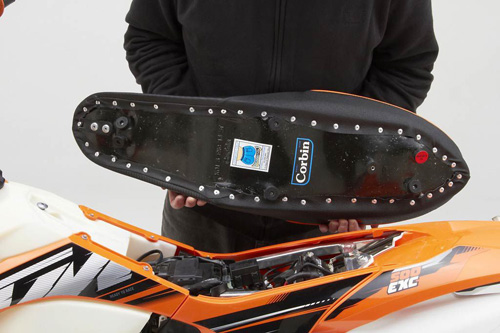 a person holding Dual Sport seat showing the back side, MPN printed and mounting brackets pre-installed