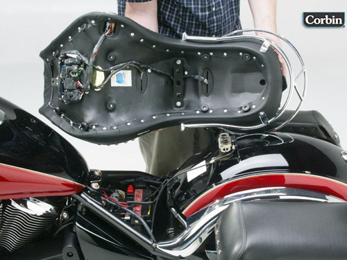 a person holding Dual Tour seat showing the rear side heater wiring, MPN printed and mounting brackets pre-installed