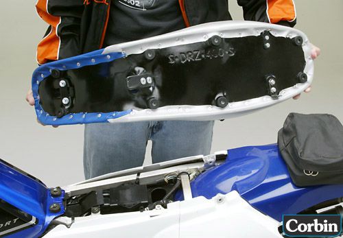 a person holding Dual Sport seat showing the back side, MPN printed and mounting brackets pre-installed