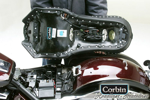 a person holding Dual Tour seat showing the rear side heater wiring harness, MPN printed and mounting brackets pre-installed