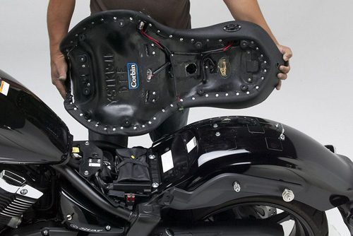 a person holding Dual Touring seat showing the rear side heater wiring, MPN printed and mounting brackets pre-installed