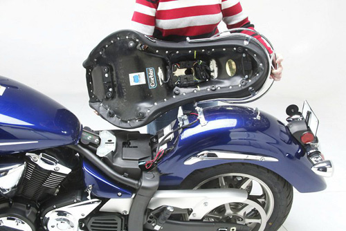 a person holding Dual Touring seat showing the rear side heater wiring, MPN printed and mounting brackets pre-installed