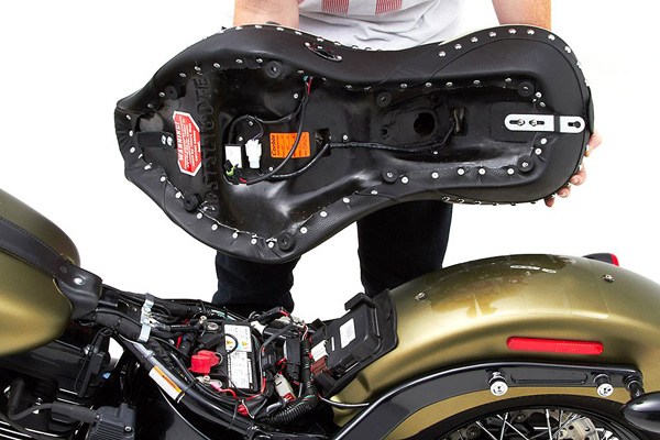 a person holding Dual Tour seat showing the rear side, MPN printed, heater wiring harness and mounting brackets pre-installed