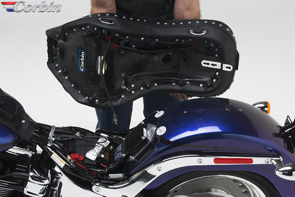 a person holding Dual Touring seat showing the rear side, MPN printed, heater wiring harness and mounting brackets pre-installed