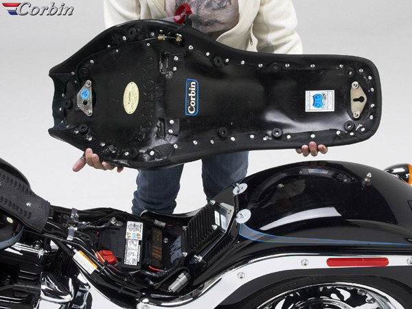 a person holding Young Guns seat showing the rear side, MPN printed, corbin's unique Key lock system and mounting brackets pre-installed