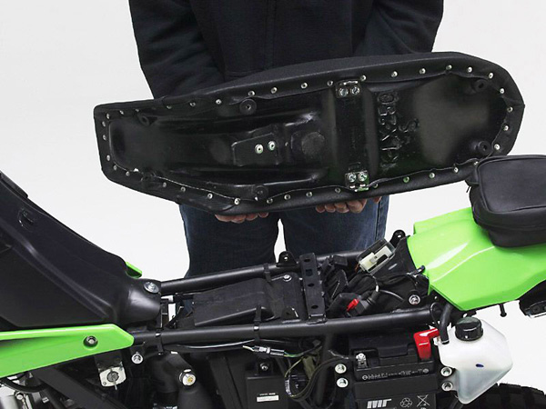 a person holding Dual Sport seat showing the rear side with MPN printed and mounting brackets pre-installed