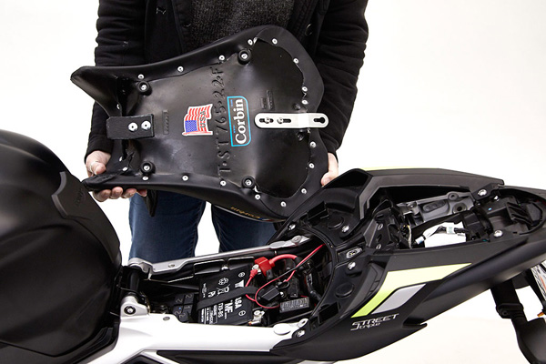 a person holding Gunfighter seat showing the rear side MPN printed with Corbin sticker and mounting brackets pre-installed