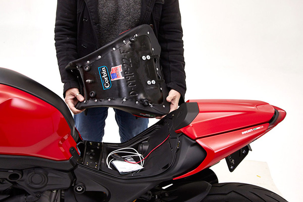 a person holding Front seat showing the rear side with MPN/Corbin sticker printed and mounting brackets pre-installed