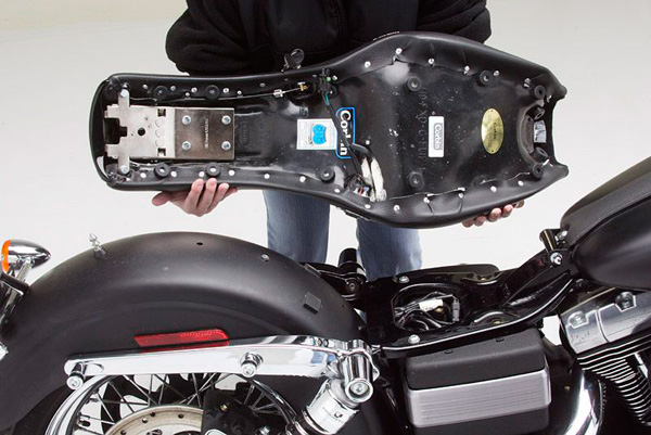 a person holding Rumble seat showing the rear side with MPN printed, mounting brackets and Corbin's new key lock pre-installed