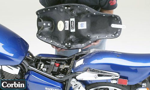 a person holding Young Gun seat showing the rear side with Front tongue and single screw into your fender at the rear pre-installed