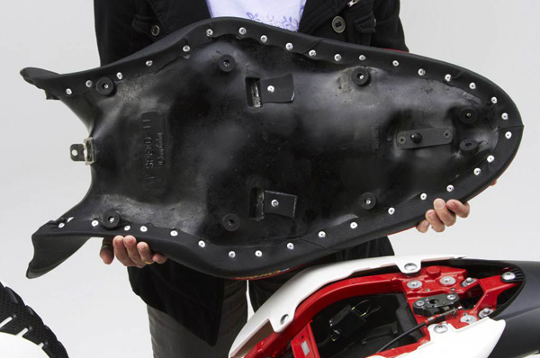 a person holding Dual seat showing the rear side with mounting brackets pre-installed