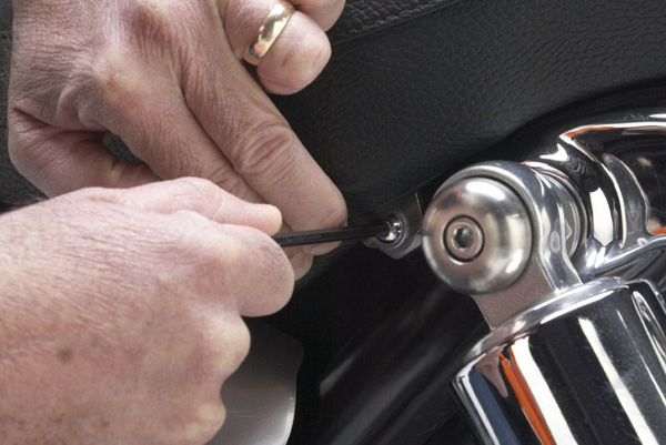 a person is fixing a motorcycle's seat by mounting bolts at the sides