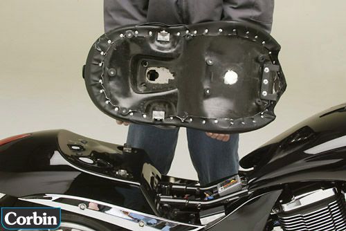 a person holding Dual Tour seat showing the rear side with mounting brackets pre-installed