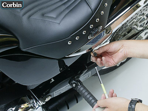 a person is holding screw driver and bolt securing the saddle by using the two stock bolts into the chassis at the sides