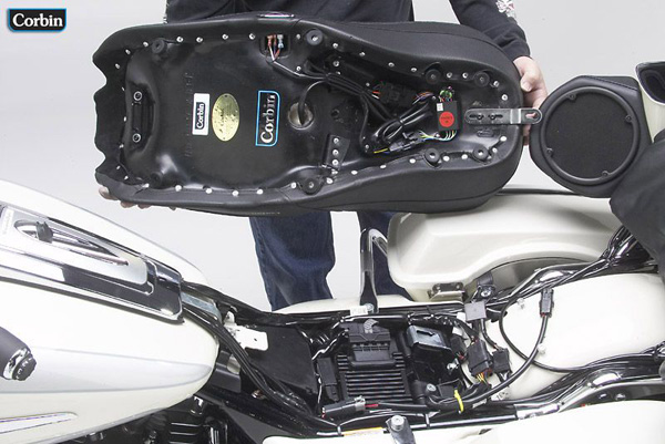 a person holding Dual Tour seat showing rear side MPN printed, heater wiring and mounting brackets pre-installed