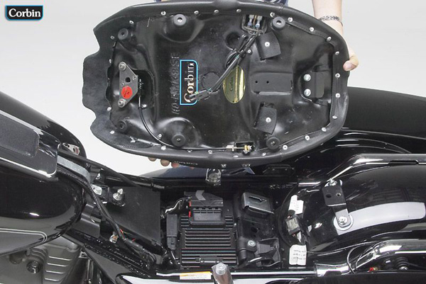 a person holding solo seat showing rear side with MPN printed, heater wiring and mounting brackets pre-installed