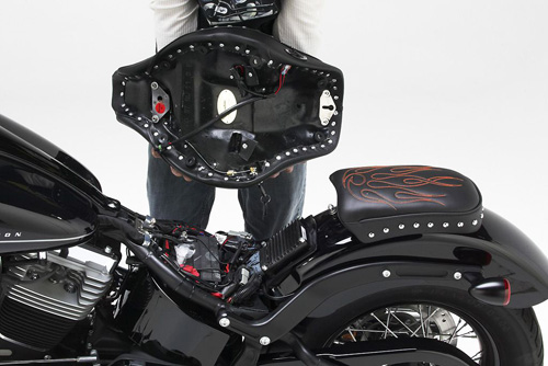 a person is holding Classic Solo seat showing rear side MPN printed, wiring harness and mounting brackets pre-installed
