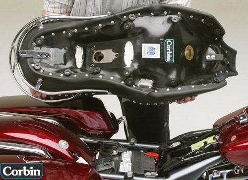 a person is holding Dual Touring seat showin rear side with MPN printed and mounting brackets pre-installed