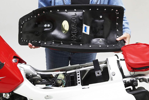 a person is holding Dual Sport seat showing rear side MPN printed and mounting brackets pre-installed