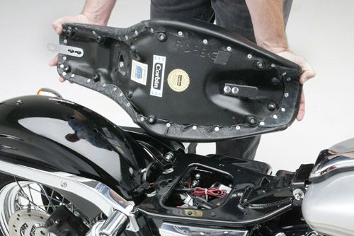 a person is holding Gunfighter seat showing rear side mounting brackets pre-installed